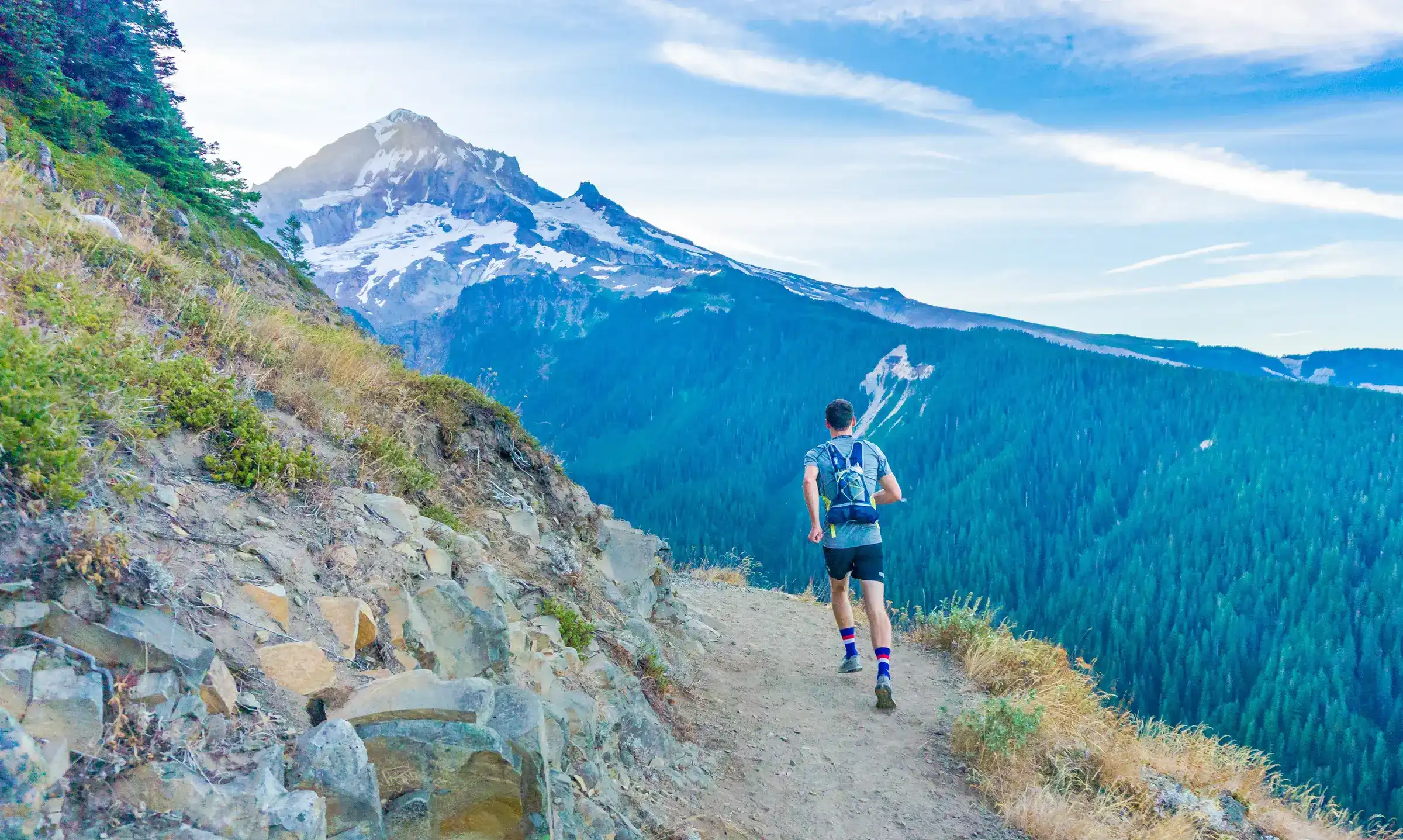 Trail runner going uphill with a mountain in the backdrop