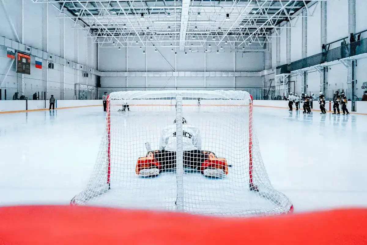 Hockey goalie looking out onto an empty rink while stretching